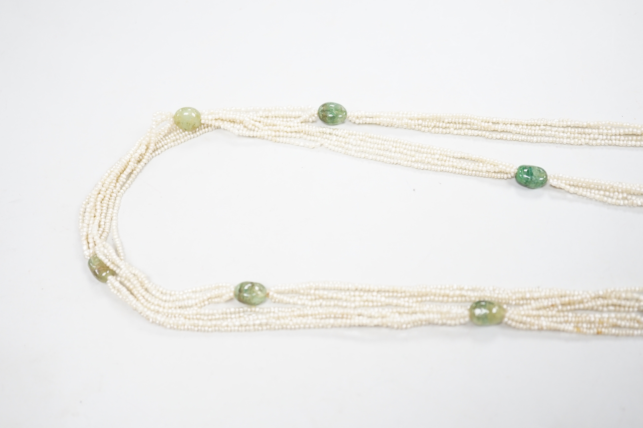 A 19th century Indian multi strand seed pearl and emerald? set long necklace, with gem set tassel drops, 176cm.